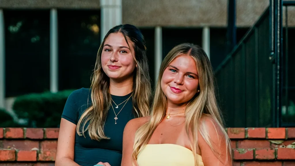 2 women sitting on the steps and smiling at the camera